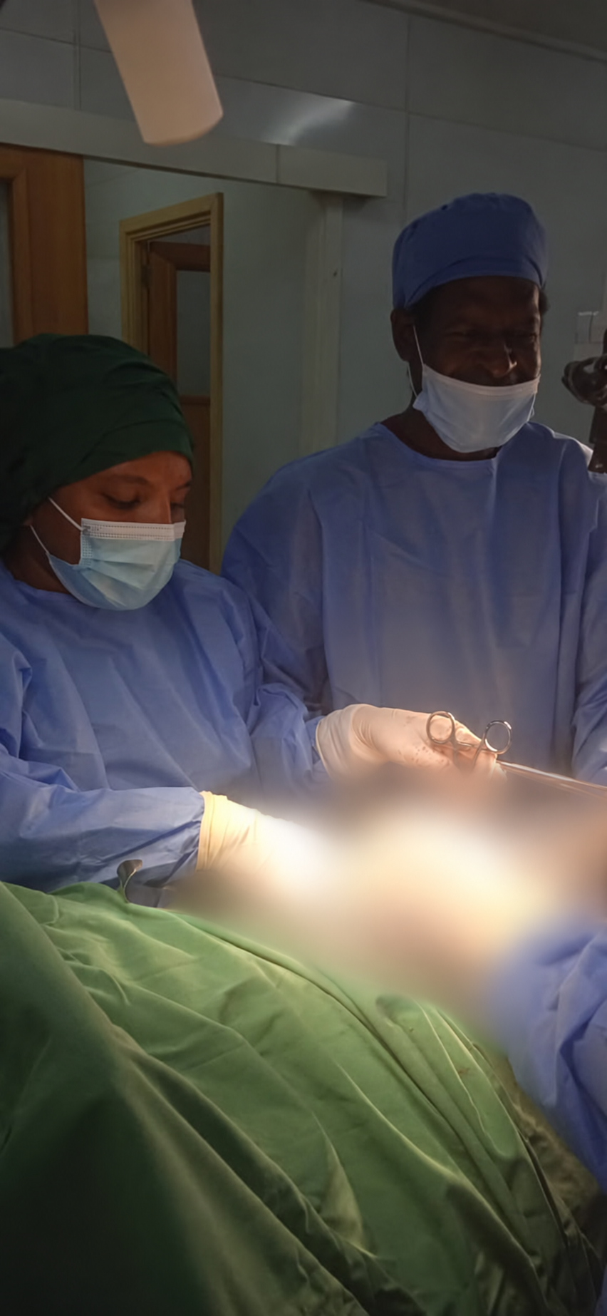 Members of the theatre team during a procedure, with sensitive clinical areas digitally blurred.