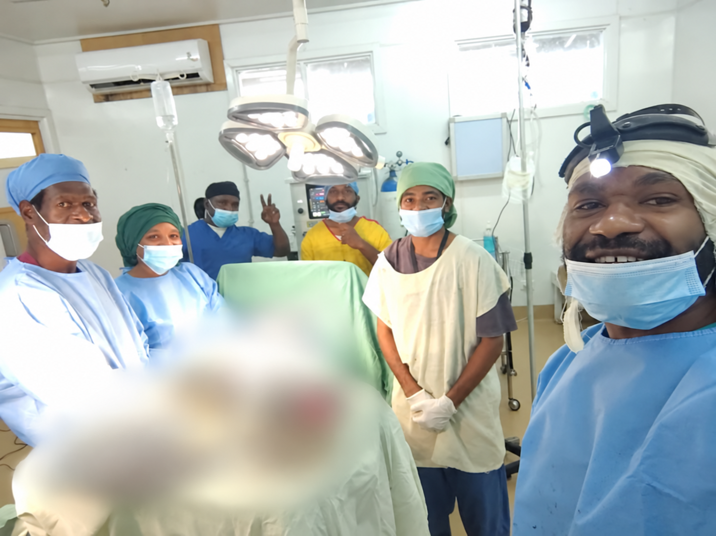 Students and hospital staff in theatre, with sensitive clinical areas digitally blurred.
